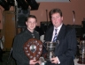 Niall Kearney presents captain Conor Hasson with the NA Division 2 Minor league Cup and B Shield